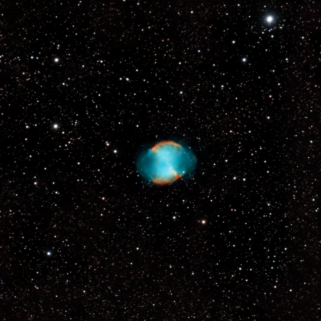 The Dumbbell Nebula glowing teal and amber against a dense field of stars